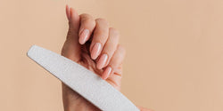Hand filing an almond-shaped nail with a white nail file, nail shapes guide